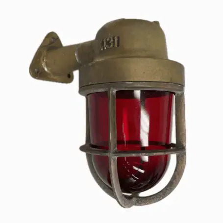 Close-up of weathered brass wall sconce with red glass globe