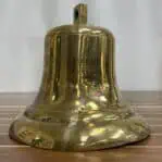 Salvaged brass ship bell side profile showing dents and service wear