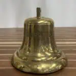 Salvaged brass ship bell close-up of MIDNIGHT SUN lettering and surface scratches