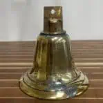 Weathered brass ship bell on wood floor – front view