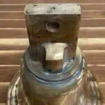 Top mount of weathered brass ship bell showing 5/8" cannon opening