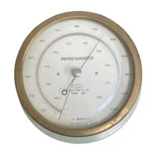 vintage brass aneroid barometer front view with clear glass face and pressure dial
